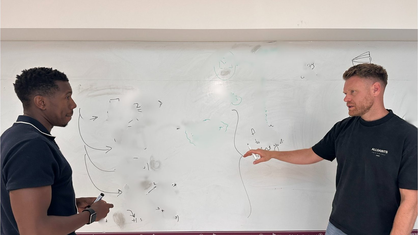 John and a client close-in at a populated wall whiteboard, working through arrows and notes