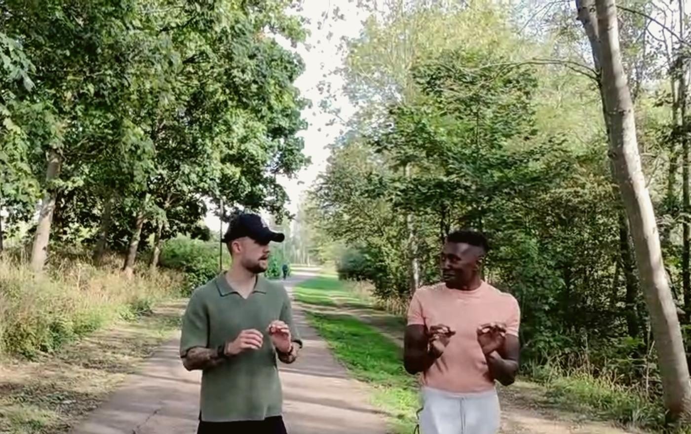 Two men talking as they walk a tree-lined path.